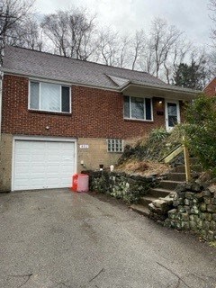 A brick house with a white garage door and a stone wall.
