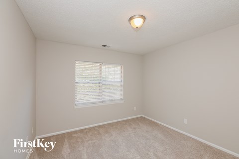 a spacious bedroom with a large window and carpeted flooring