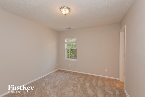the spacious living room with carpeting and a window