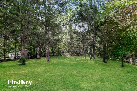 a large backyard with trees and a fence