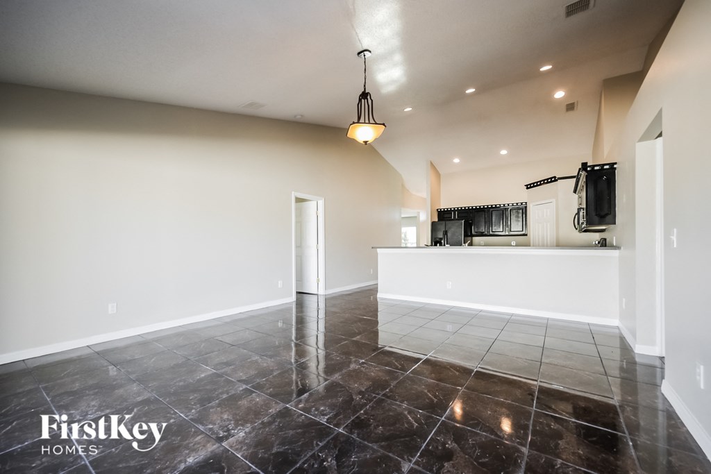 an empty living room and kitchen with tile flooring