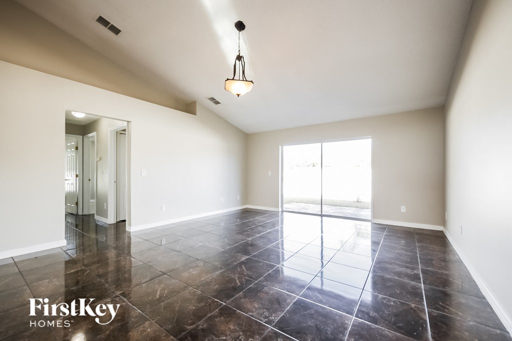 an empty living room with tile floors and a large window