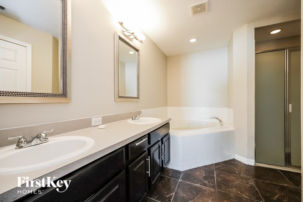 a bathroom with two sinks and a tub and a mirror