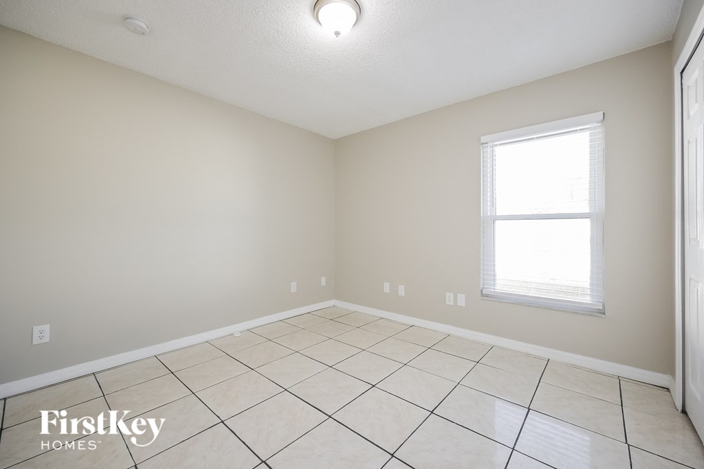 the spacious living room with tiled floors and a window