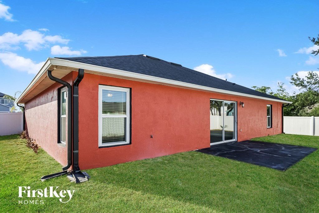 a small red house with a black roof and a yard