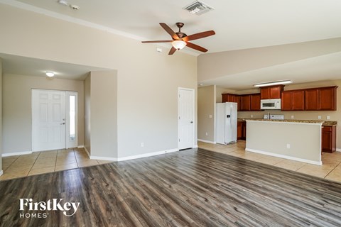 A spacious living room with wood flooring and a ceiling fan.