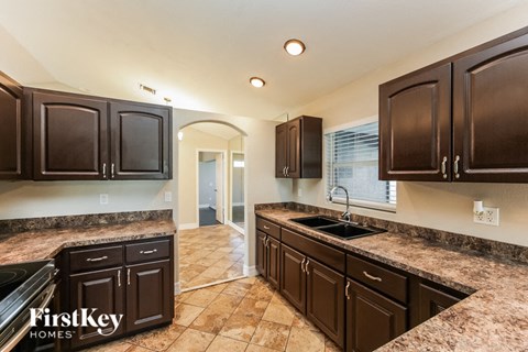 a kitchen with dark cabinets and granite counter tops and a sink