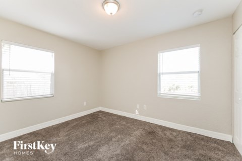 a bedroom with a carpeted floor and two windows