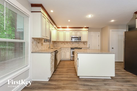 A kitchen with white cabinets and a wooden floor.