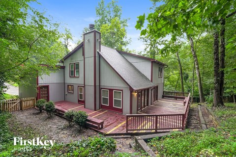 A house with a red deck is surrounded by trees.