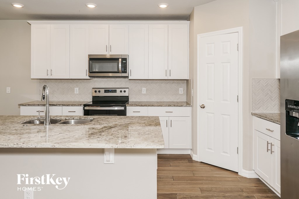 A kitchen with a marble countertop and white cabinets.
