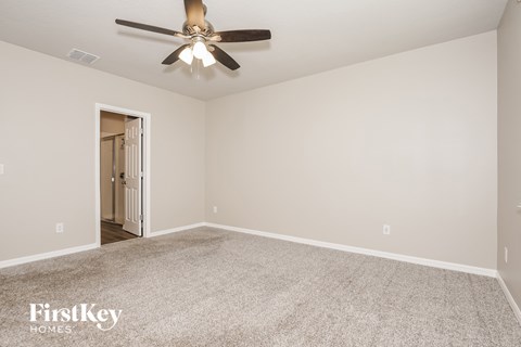 A spacious room with a ceiling fan and carpeted floor.
