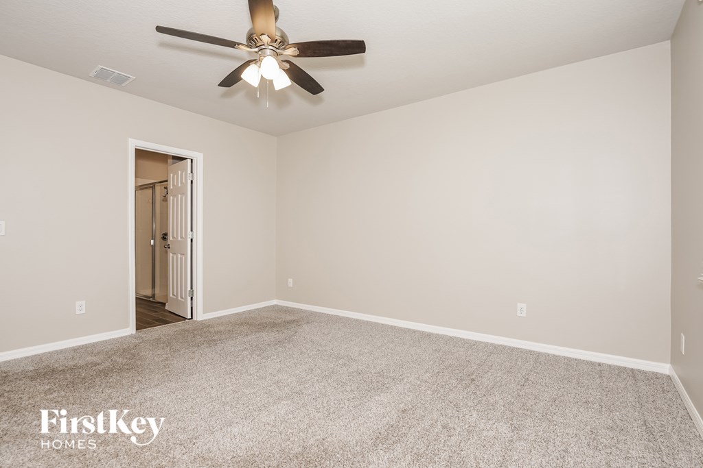 A spacious room with a ceiling fan and carpeted floor.