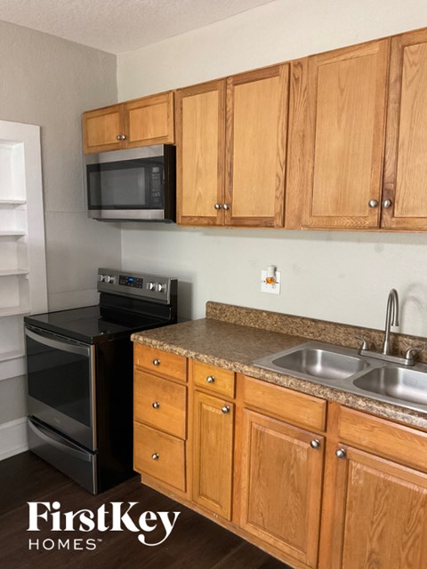 A kitchen with wooden cabinets and a black oven.