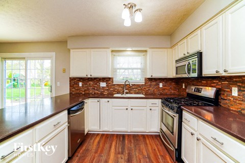 A kitchen with white cabinets and a brick backsplash.