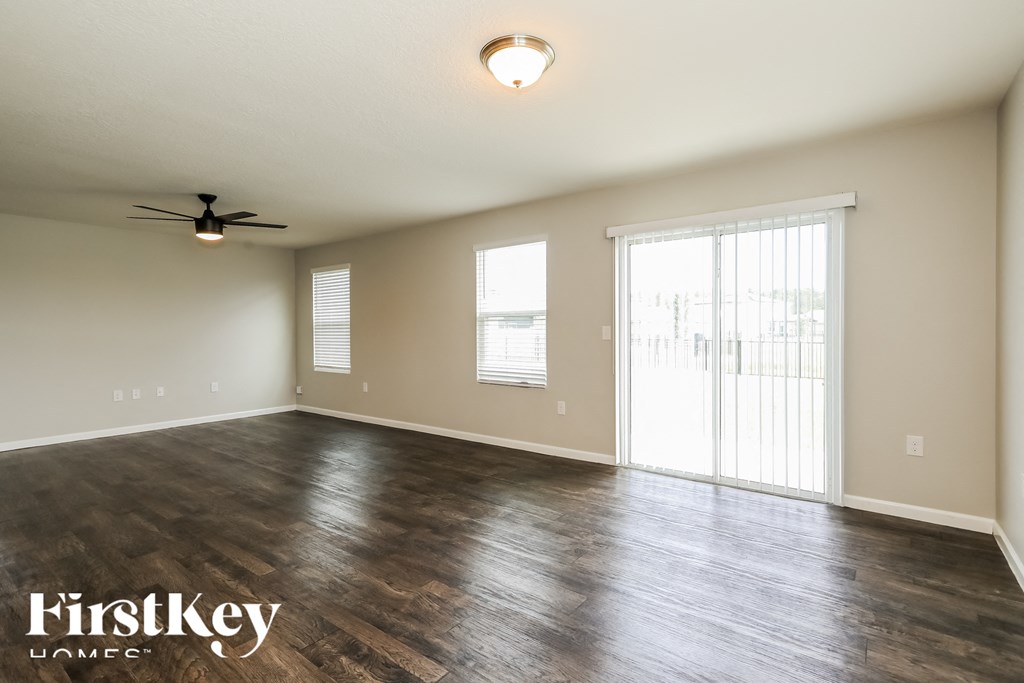 an empty living room with wood floors and a ceiling fan