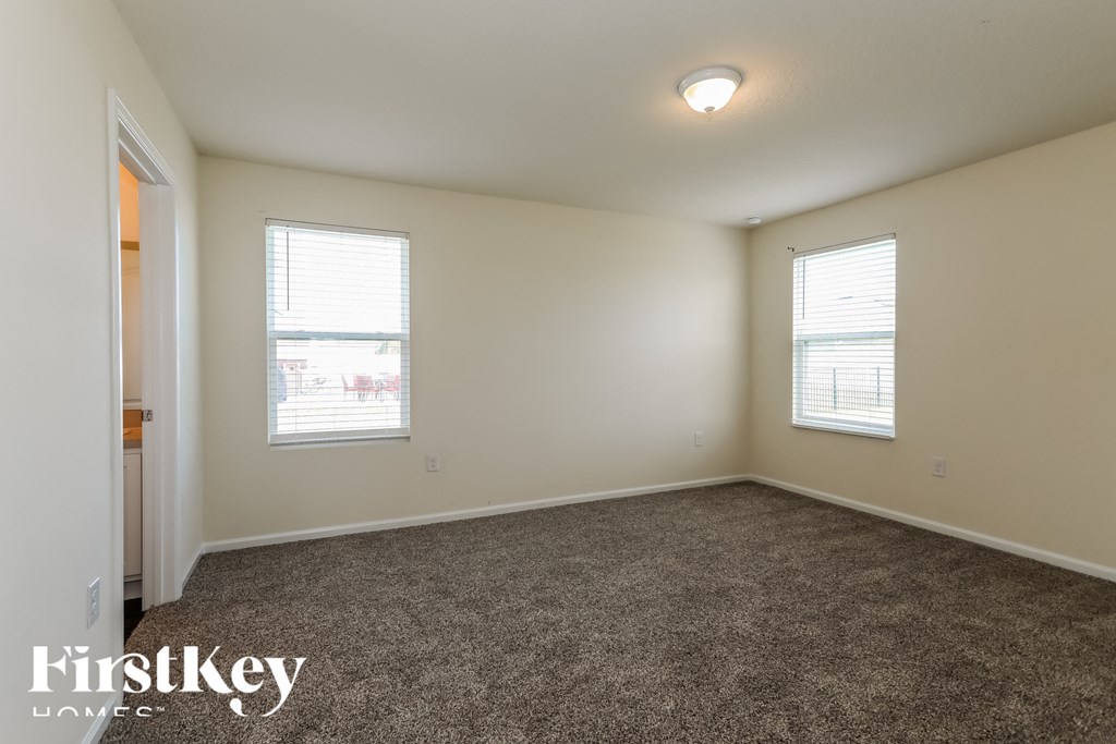 a bedroom with a carpeted floor and two windows