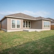 a brown house with a grass yard and a blue sky