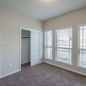an empty living room with three windows and a door