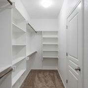 a walk in closet with white shelves and a white door