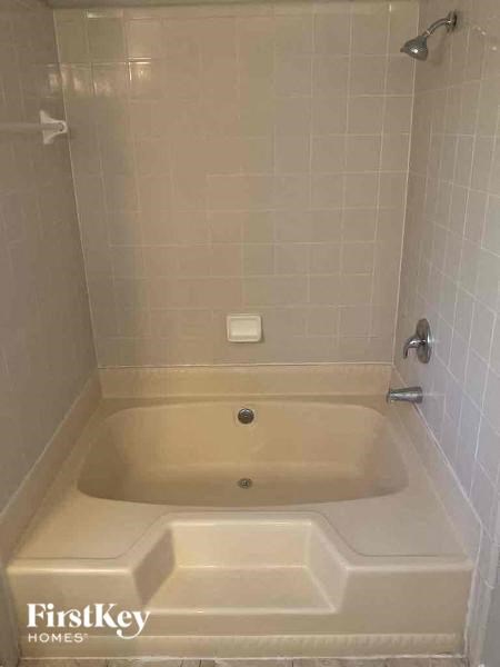 A beige bathtub in a bathroom with a shower head.