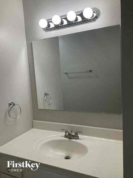 A bathroom sink with a mirror above it and lights on the wall.