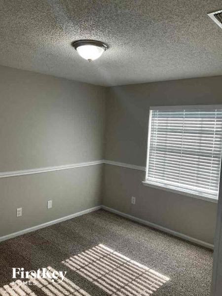 A room with a window and a rug on the floor.
