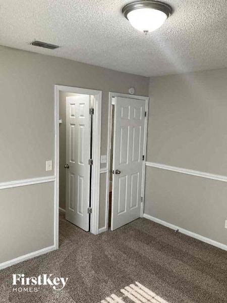 A room with two white doors and a carpet on the floor.