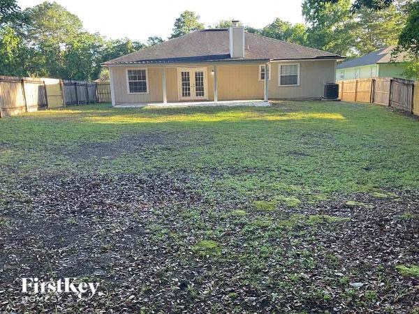 A small house with a fenced yard in front of it.