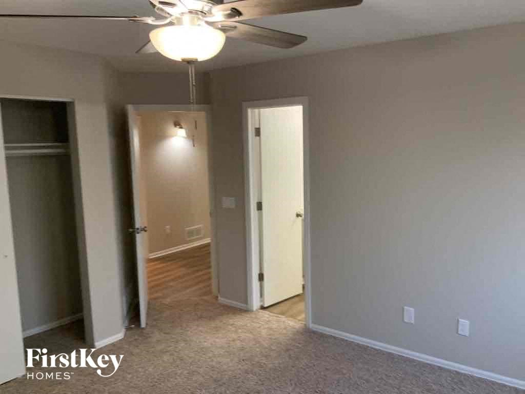 an empty living room with a ceiling fan and a door to a closet