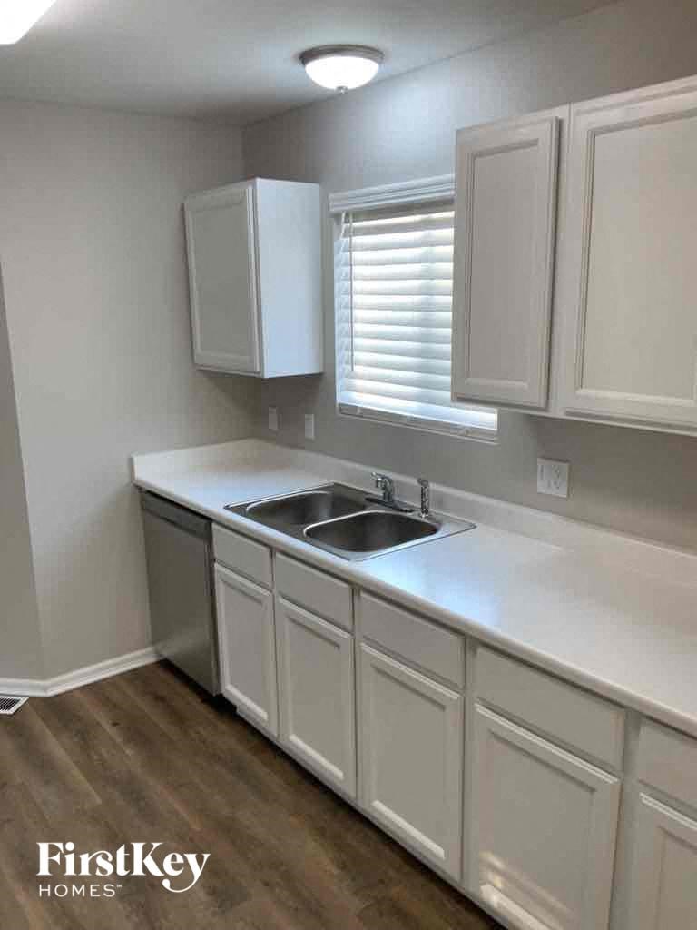 an empty kitchen with a sink and white cabinets