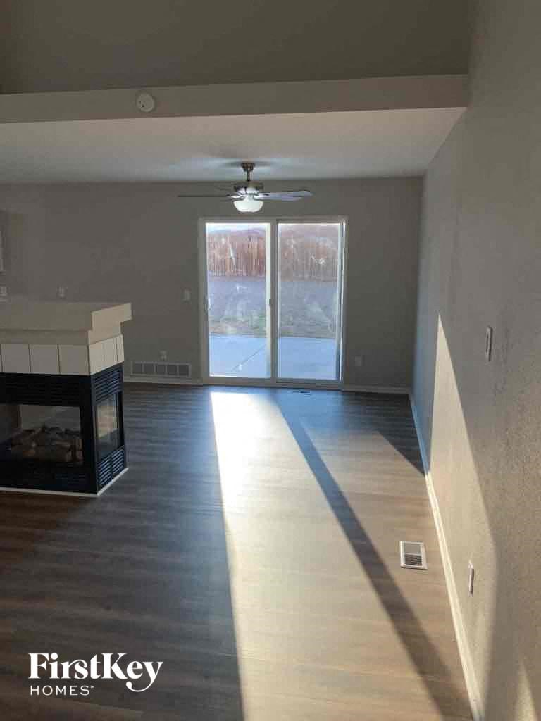 an empty living room with a fireplace and a ceiling fan