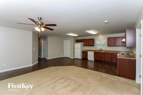 an empty living room and kitchen with a ceiling fan
