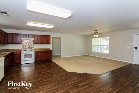 an empty kitchen and living room with wood flooring and a rug
