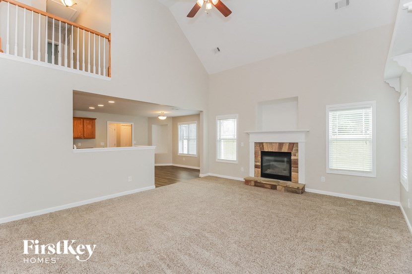A spacious living room with a fireplace and a carpeted floor.