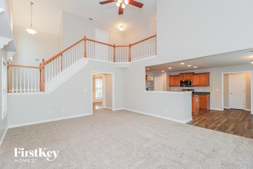 A spacious living room with a staircase and a ceiling fan.