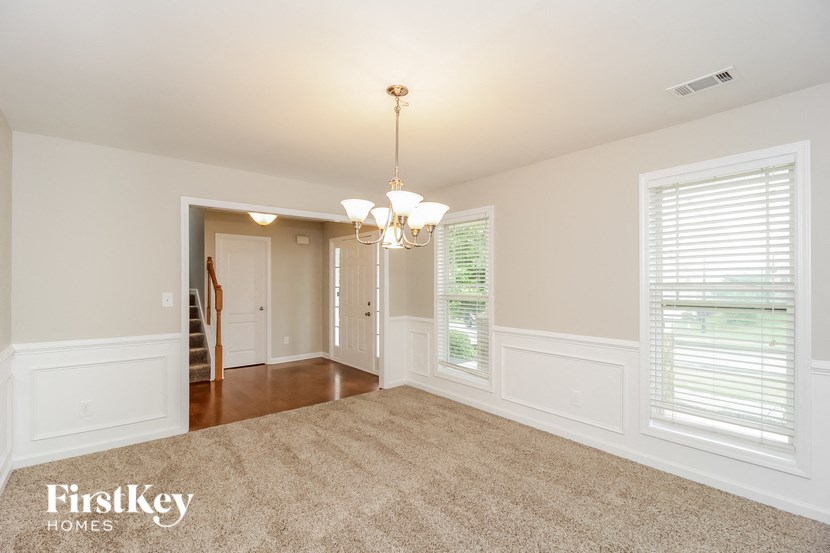 A spacious room with a chandelier and a carpeted floor.