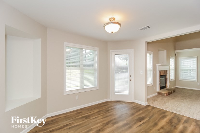 A spacious room with wooden floors and a fireplace.