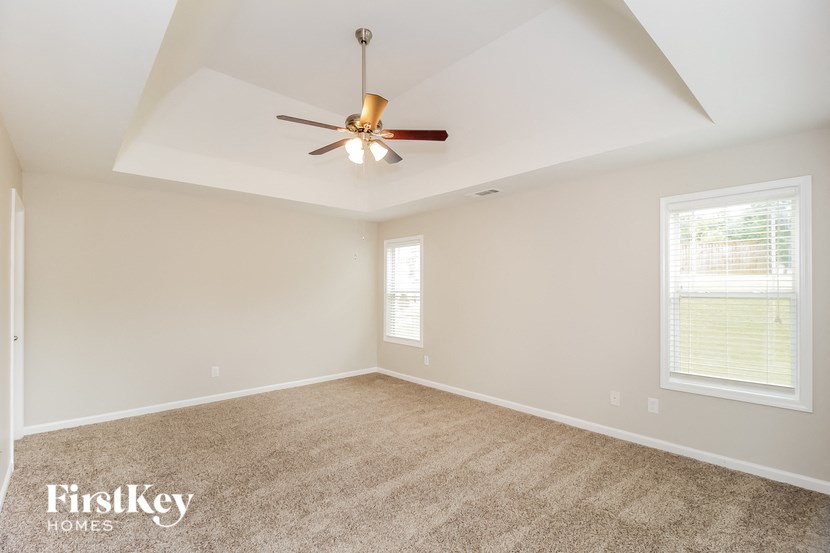 A spacious room with a ceiling fan and carpeted floor.