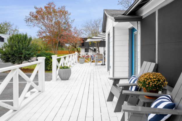 a white deck with blue and white chairs and a gray house