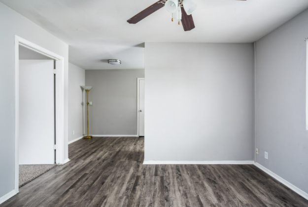 an empty living room with white walls and a ceiling fan