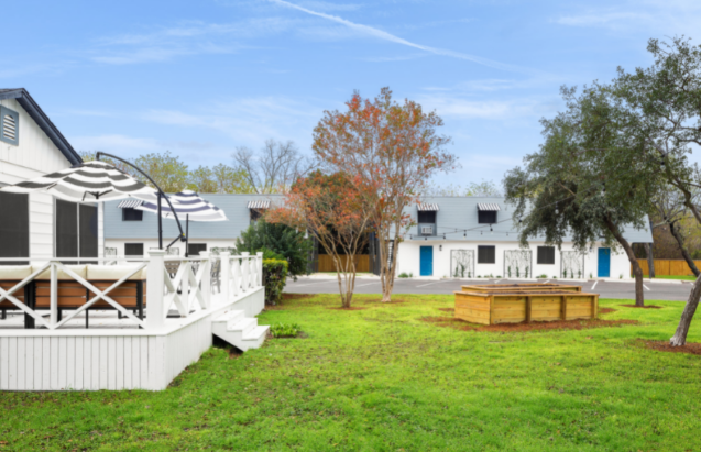 a yard with a deck and a picnic table in front of a building