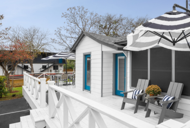 the cottage has a deck with chairs and umbrellas