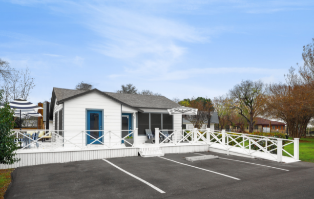 a white house with a white fence and a parking lot