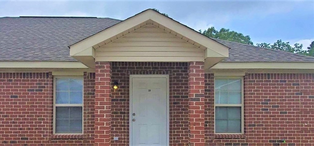 A red brick house with a white door and windows.