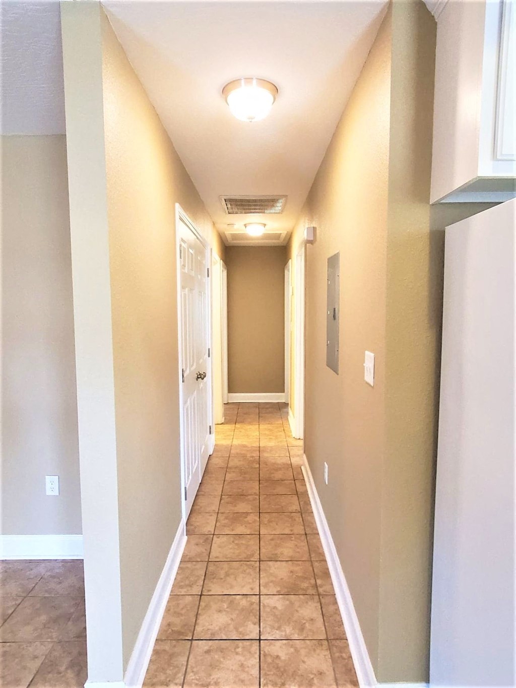 a long hallway with a white door and tile floors
