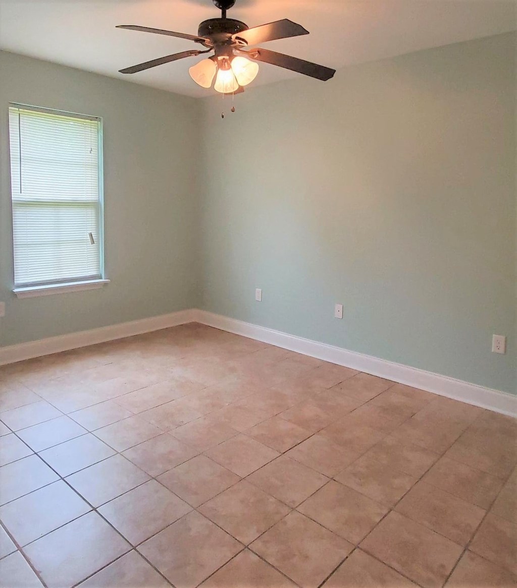 a empty room with a ceiling fan and a tiled floor