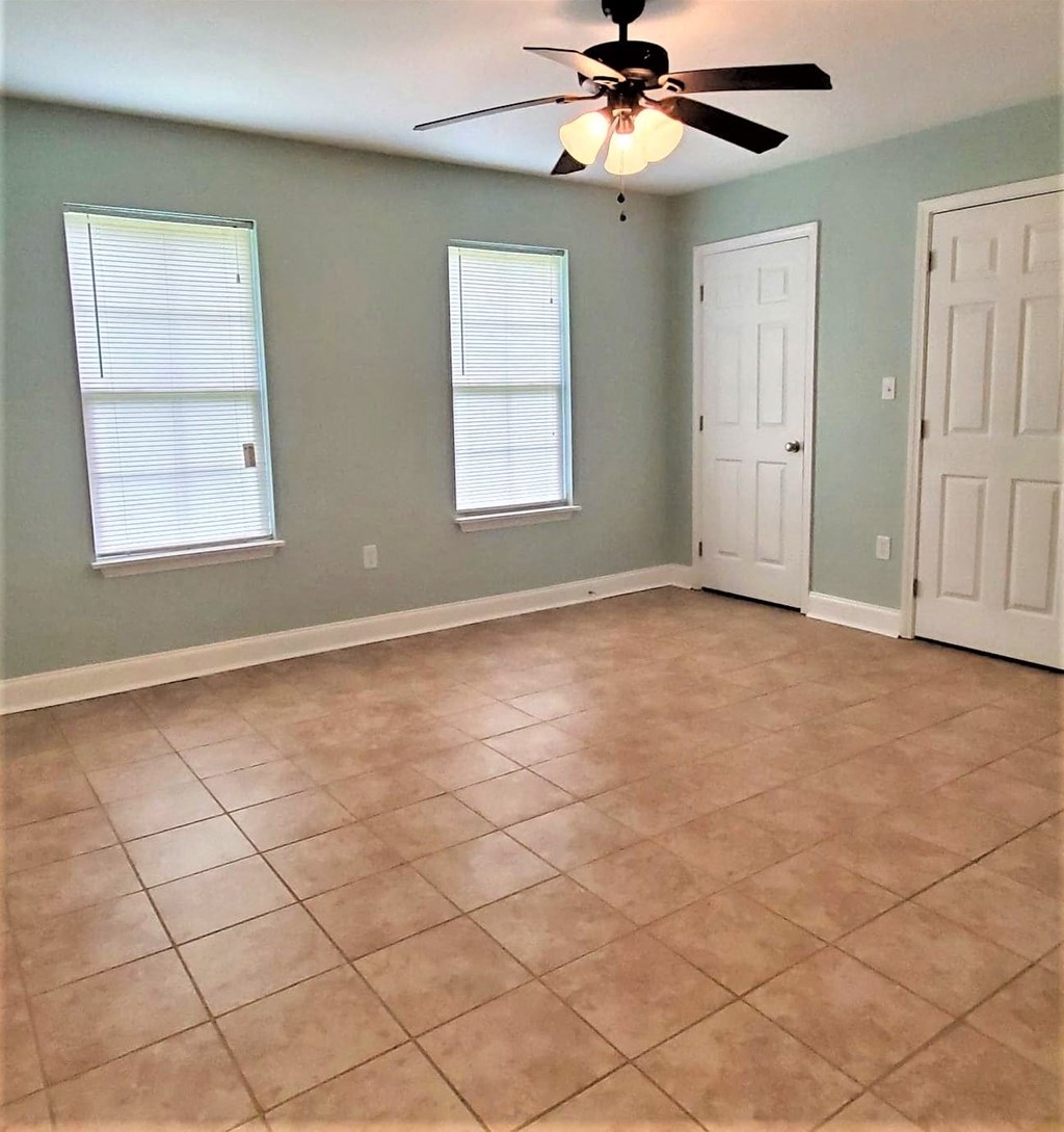an empty living room with a ceiling fan and a tiled floor
