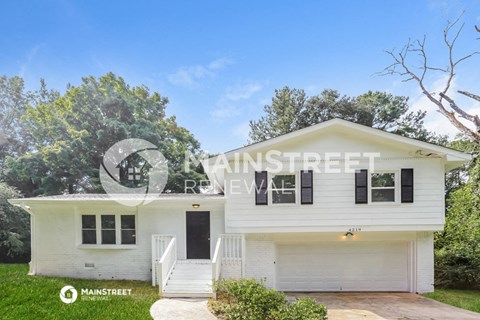 a small white house with a lawn and trees