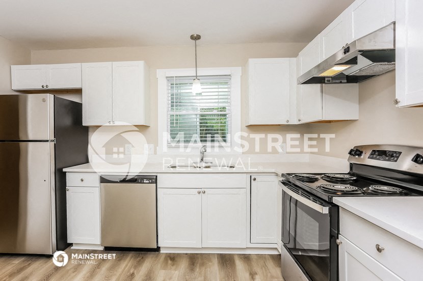 a renovated kitchen with white cabinets and stainless steel appliances